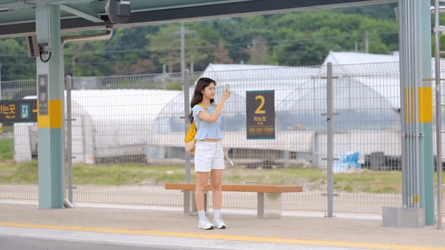 기차역 플랫폼에서 사진을 찍으며 기다리는 여성