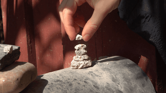 Hands that build tower by stacking silver stones