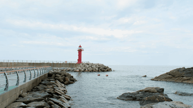 A red lighthouse by the rocky seashore
