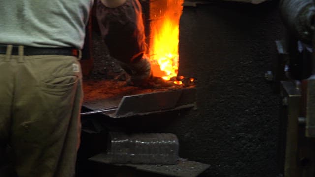 Worker handling molten metal in a furnace