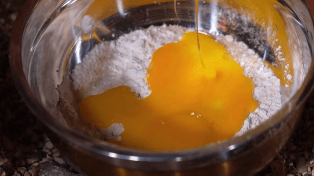 그릇 안 밀가루에 계란을 붓는 장면