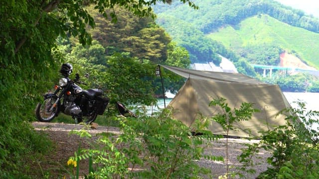 Camping by a lakeside with a motorcycle on a sunny day