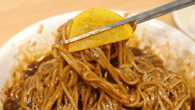 단무지를 올린 짜장면을 집은 젓가락