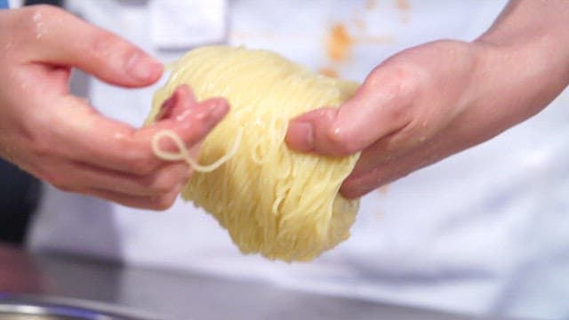 Neatly placing noodles in a metal bowl