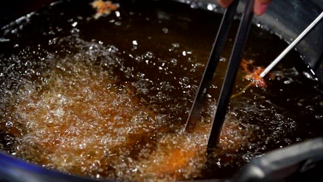 Frying pork in hot oil with tongs