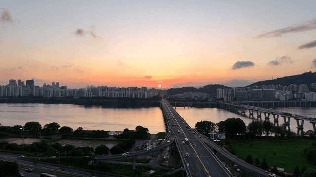 Sunset over a city with a river and bridge