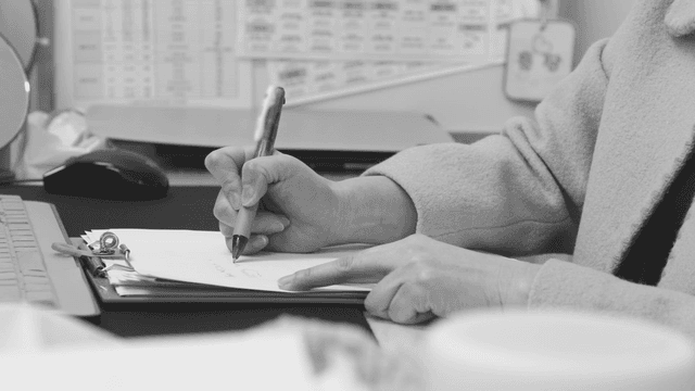 책상에서 메모를 하는 사람