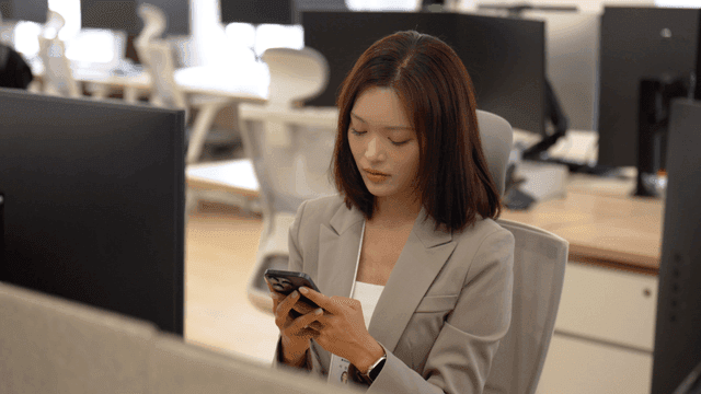 Female office worker checking her phone in office