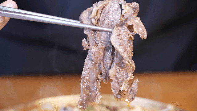 Chopsticks laden with stew meat with beef and dumplings