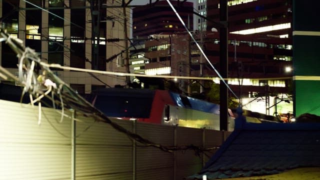 밤에 도시 건물들 사이 철도를 지나가는 열차