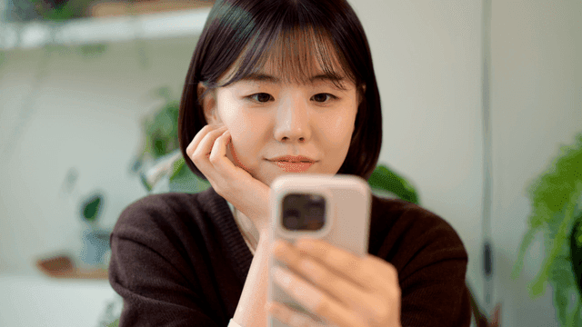 Young woman smiling while looking at her smartphone