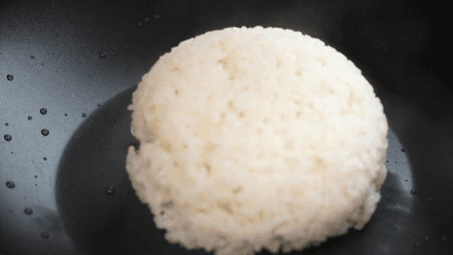 Steamed rice being placed in a pan