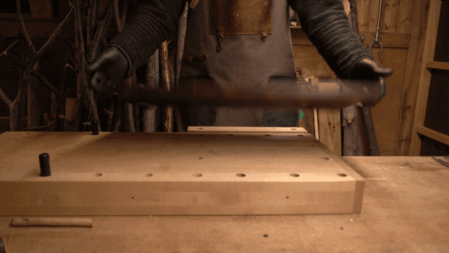 금속 손잡이가 박힌 나무판을 뒤집어 보는 장인