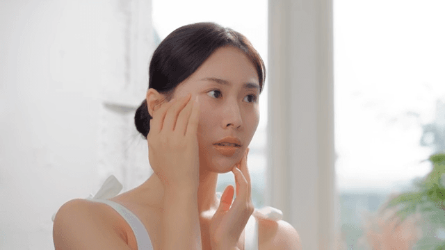 Woman touching her face with a worried expression in a bright room