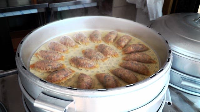 Kimchi dumplings steaming in a steamer in the kitchen