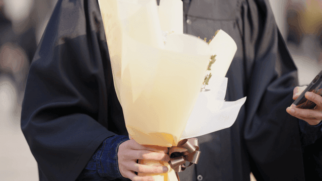 Graduate holding a bouquet and phone