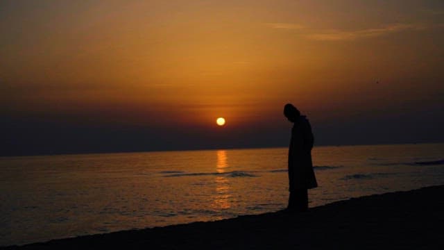 Silhouette of a person at sunset by the sea