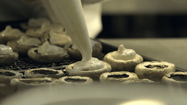 Mushrooms being filled with creamy sauce