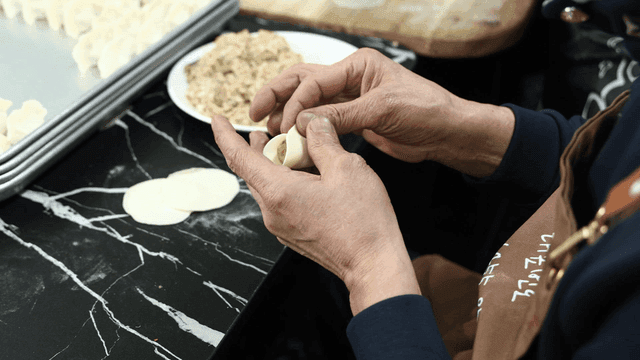 Hands making dumplings with filling