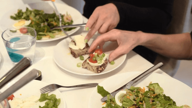 A person enjoying a meal by putting cheese on bread