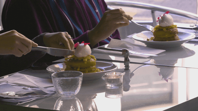 Pancakes topped with ice cream eaten with fork and knife