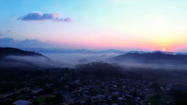 안개 낀 언덕과 함께하는 고요한 마을의 일출
