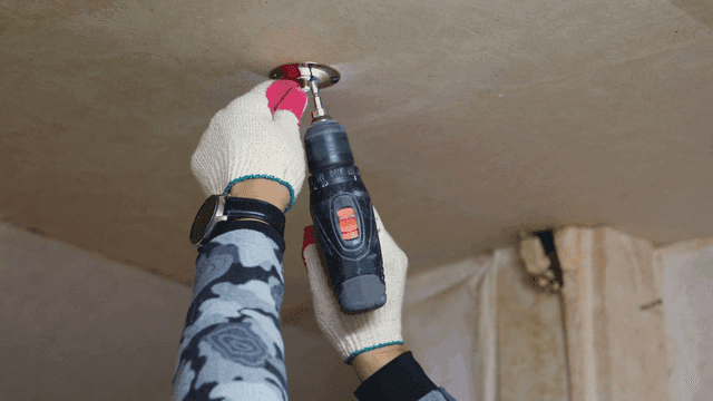 천장에 연기 감지기를 설치하는 사람