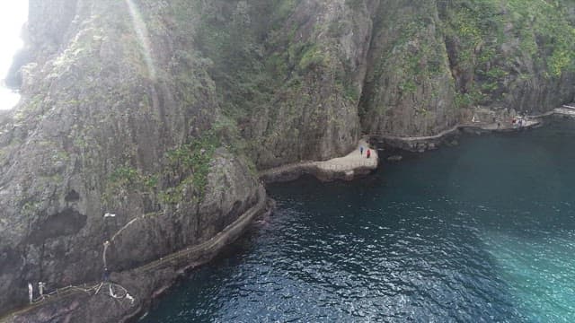 햇빛에 반짝이는 바다 물결과 바위 절벽 산책로