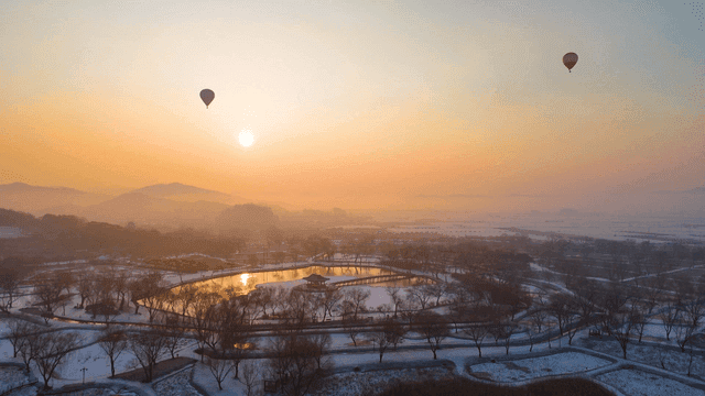 Hot air balloons above serene landscape at sunset