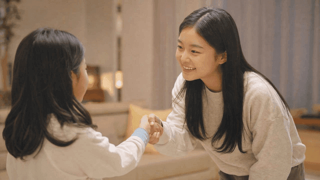 Two girls shaking hands in a cozy room