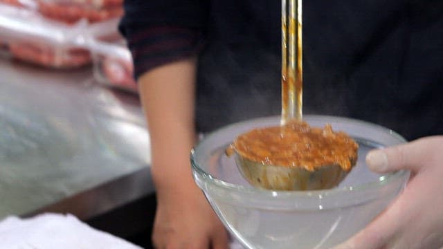 Pouring sauce over hamburger steak plated with rice and bread