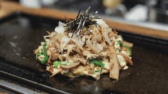Okonomiyaki cooking on a hot griddle