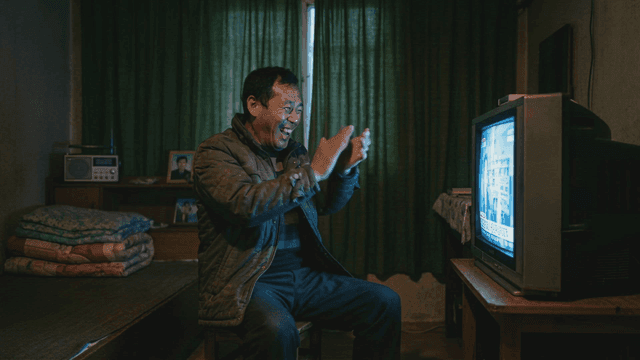 Middle-aged man happy watching TV in dark room