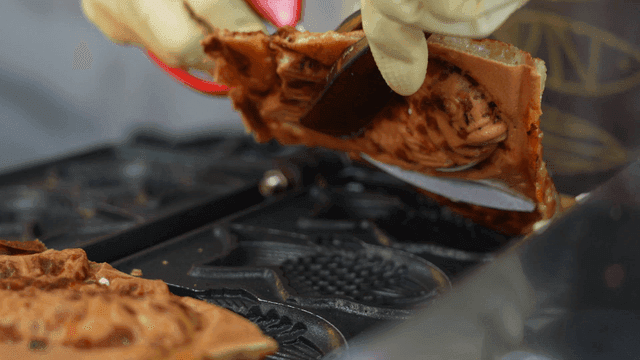 Street vendor cutting baked bungeoppang with scissors
