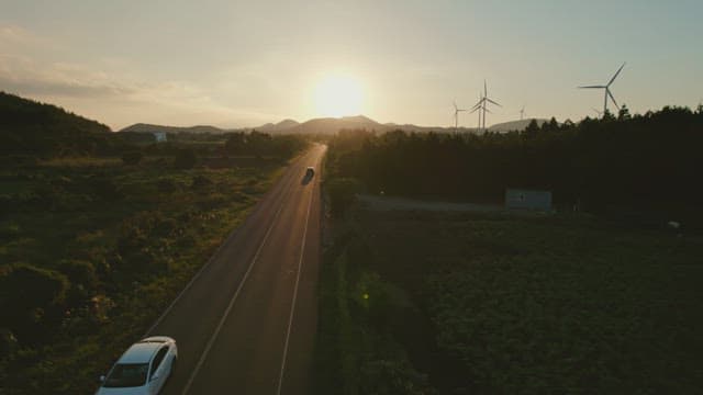 Scenic road with wind turbines at sunset