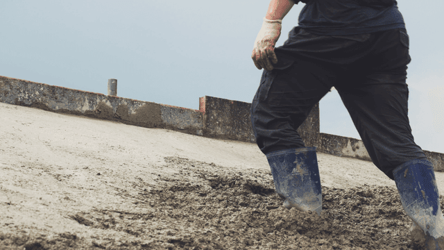 경사면에서 젖은 콘크리트를 다듬는 작업자