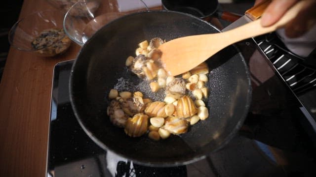 Stir-frying abalone and garlic in oil in a pan