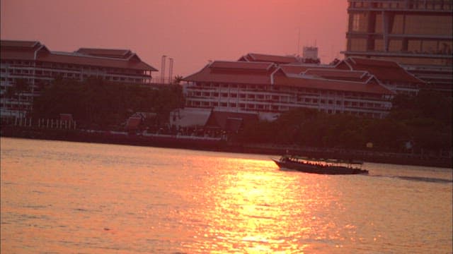 Boat on a river at sunset near buildings