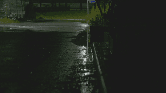 Rain falling on a quiet wet street at night