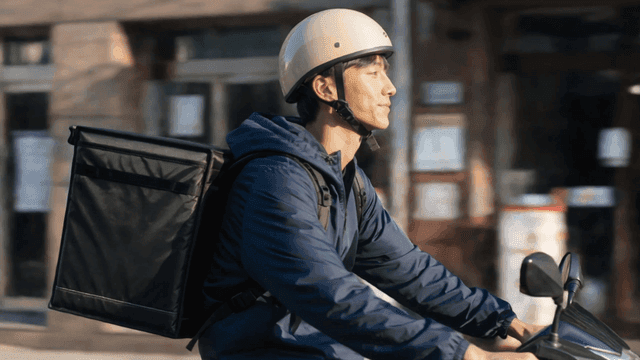도로를 달리는 오토바이 배달원