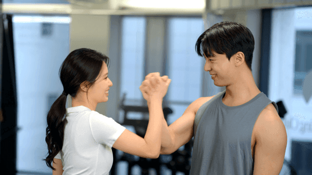 헬스장에서 웃으며 손을 잡고 서로 응원하는 커플