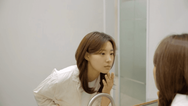 거울 속 피부를 살펴보는 여성