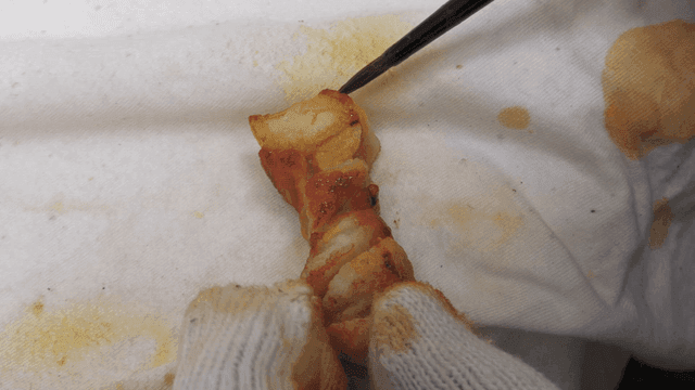Craftsman painting model of grilled pork belly with brush using his gloved hands.