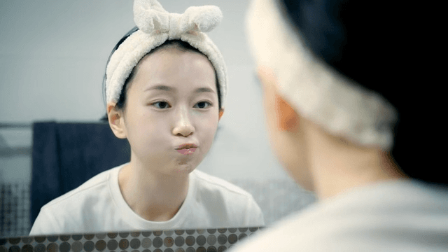 Woman gargles in front of mirror in bathroom