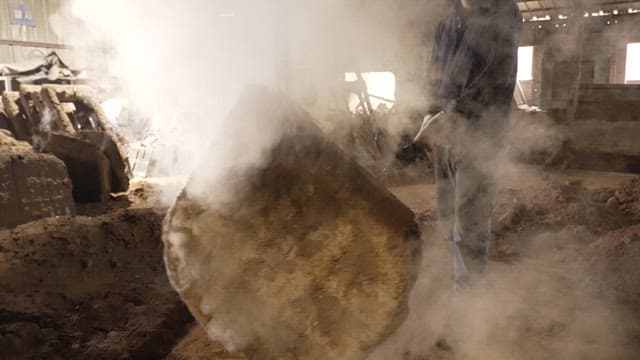 작업자가 큰 금속 몰드를 다루는 모습