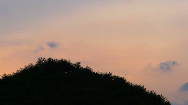 Sunset red sky above a forested hill with clouds