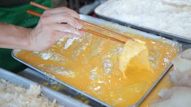 생선 튀김을 만들기 위해 계란물을 입힌 생선에 튀김옷 입히기