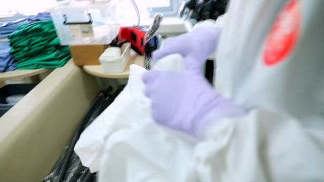 방호복을 착용한 사람이 의료 장비를 다루는 모습