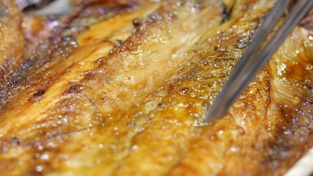 Cutting the glossy, golden grilled mackerel with chopsticks