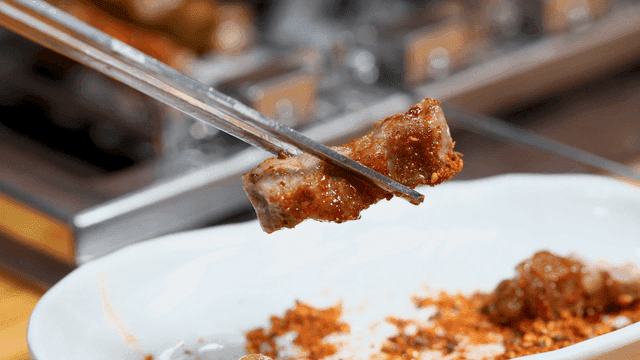 Lamb skewers dipped in cumin, lifted with chopsticks